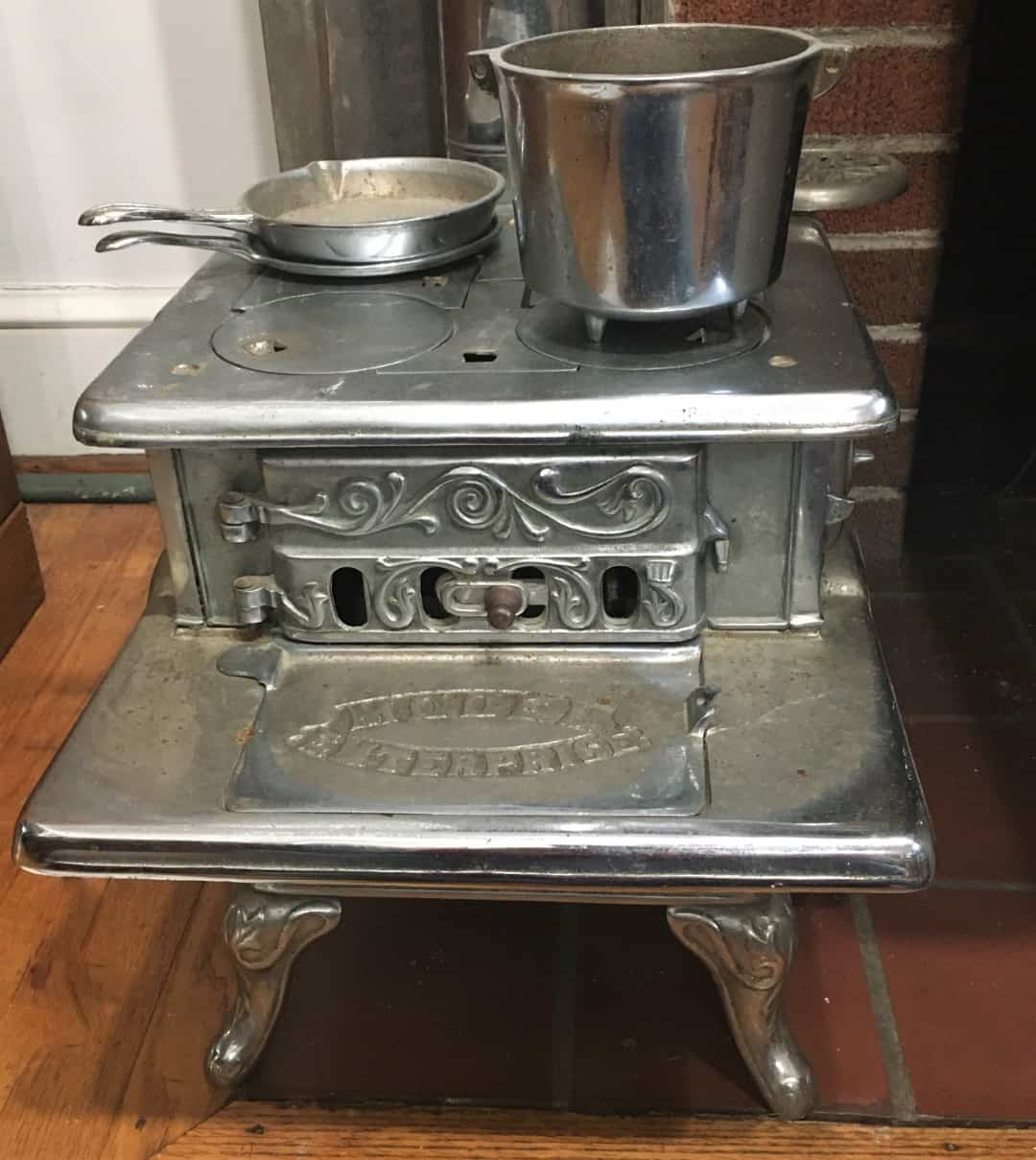 Front and cooking surface of scale model stove with skillets and pot.
