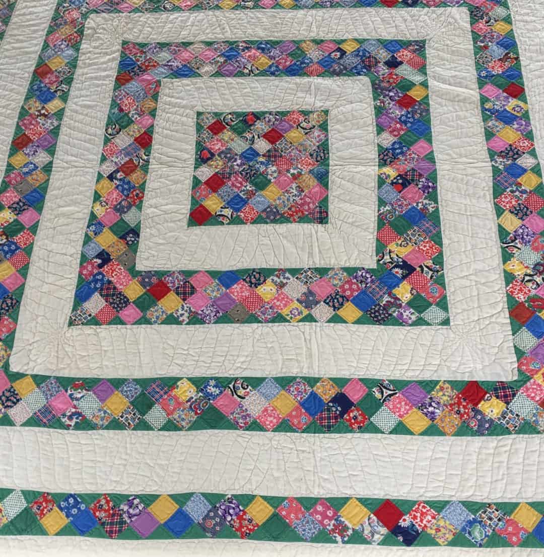Colorful quilt with pieced frames around a central square.